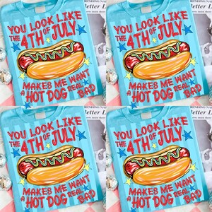 May include: Light blue t-shirts with a graphic of a hot dog and the text "YOU LOOK LIKE THE 4TH OF JULY MAKES ME WANT A HOT DOG REAL BAD". The design includes stars and a cartoon hot dog.