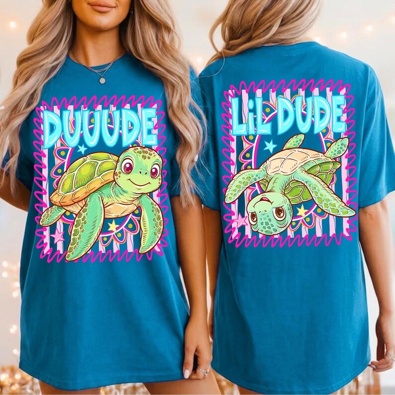 May include: Teal t-shirt with a cartoon turtle design. The front says "DUUUDE" and the back says "Lil DUDE". The turtle is green and yellow, with pink accents. The design is framed by a pink and white wavy border.