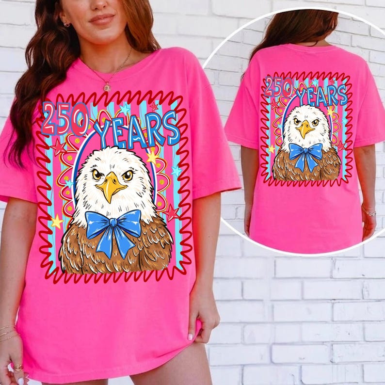 Pu&ograve; includere: Una maglietta rosa acceso con una grafica di un'aquila con un papillon blu, incorniciata dal testo "250 YEARS". Anche il retro della maglietta mostra la grafica dell'aquila e il testo. La maglietta &egrave; in stile casual e oversize.