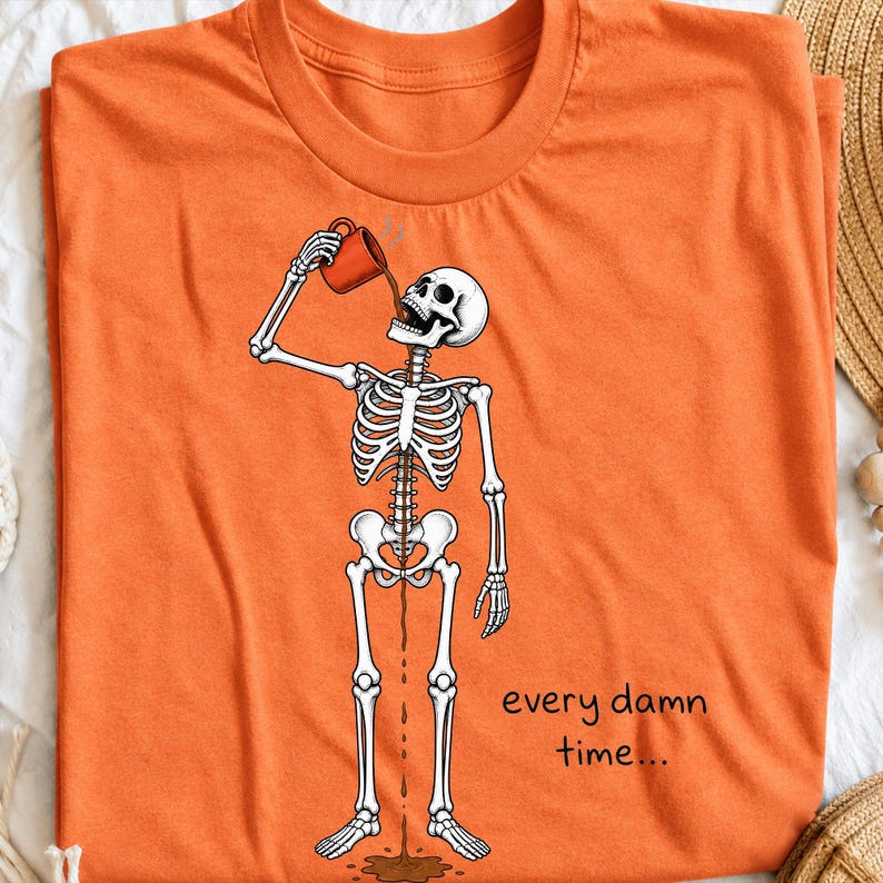 May include: An orange t-shirt featuring a graphic of a white skeleton drinking from a red mug. The coffee flows through the skeleton's body and out onto the ground. The text "every damn time..." is printed in black on the lower right side.