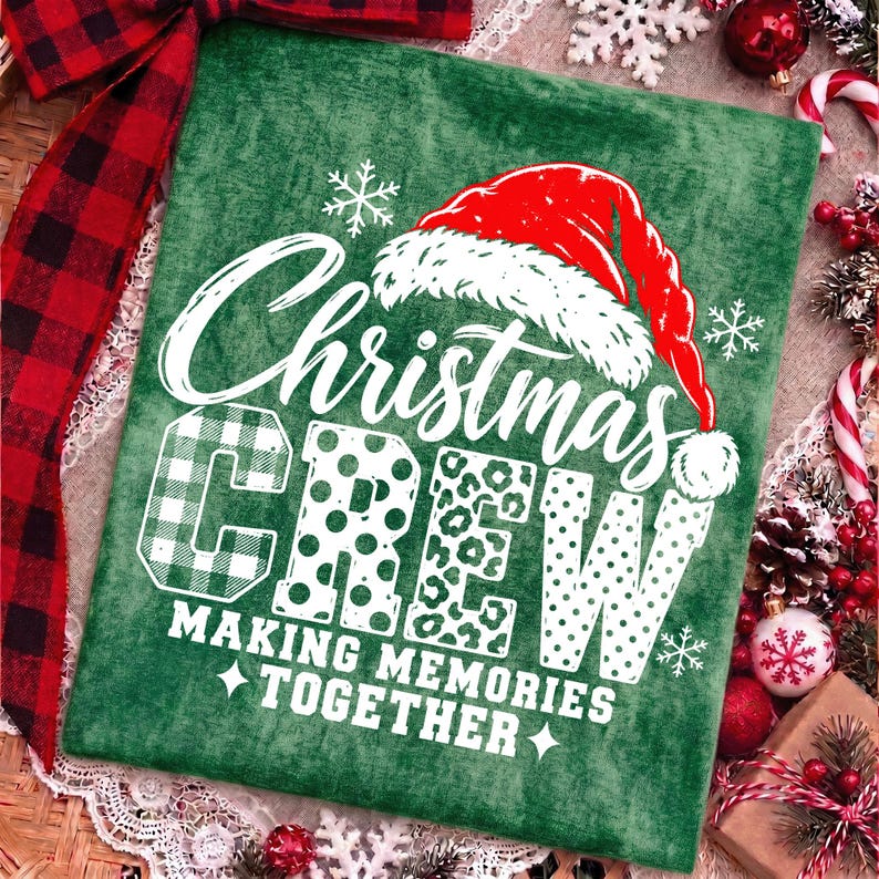 May include: A green fabric item featuring a white graphic that reads Christmas CREW MAKING MEMORIES TOGETHER. The text is topped with a red and white Santa hat and accented with white snowflakes. The letters feature plaid, polka dot, and leopard patterns.