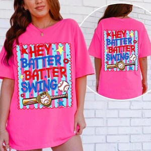K&ouml;nnte beinhalten: Leuchtend pinkes T-Shirt mit dem Schriftzug "Hey Batter Batter Swing" in Blau und Rot, zusammen mit einer Baseball- und Schl&auml;gergrafik. Die R&uuml;ckseite des Shirts zeigt das gleiche Design. Das Shirt hat kurze &Auml;rmel und eine lockere Passform.
