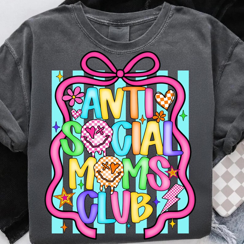 K&ouml;nnte beinhalten: Dunkelgraues Sweatshirt mit einem farbenfrohen Aufdruck &bdquo;ANTI SOCIAL MOMS CLUB&ldquo;. Das Design zeigt eine rosa Schleife, Smiley-Gesichter, Blumen, Herzen, Sterne und einen Blitz auf hellblauem Streifenhintergrund.