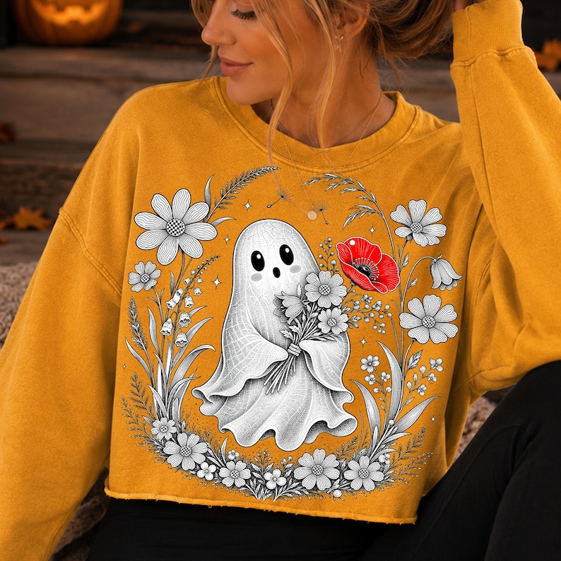 K&ouml;nnte beinhalten: Ein senfgelbes Langarm-Sweatshirt mit einem Grafikdruck eines wei&szlig;en Geistes, der einen Blumenstrau&szlig; h&auml;lt. Das Design zeigt schwarz-wei&szlig;e Strichzeichnungen von Blumen um den Geist herum, erg&auml;nzt durch eine einzelne leuchtend rote Mohnblume.