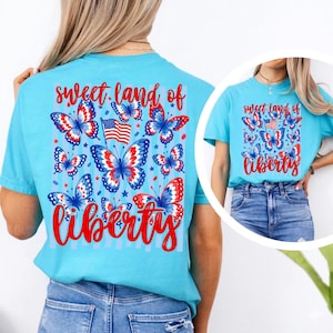 K&ouml;nnte beinhalten: Ein hellblaues T-Shirt mit einem Grafikdruck aus roten, wei&szlig;en und blauen Schmetterlingen, einer kleinen amerikanischen Flagge und dem roten Text "sweet land of liberty". Das Design ist auf der R&uuml;ckseite und vorne in einem runden Einsatz zu sehen.