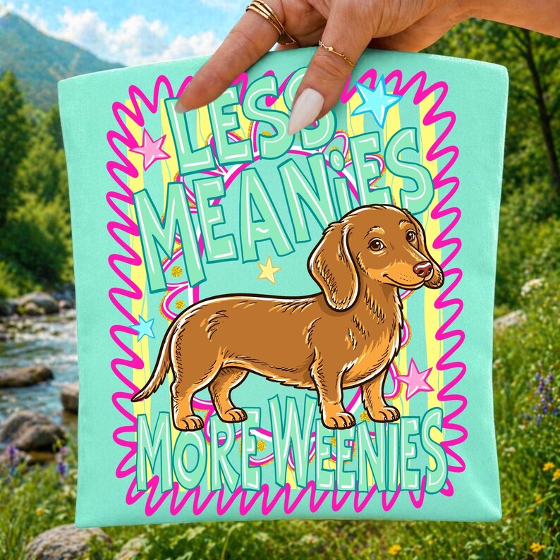 High-resolution PNG digital design featuring a cheerful wiener dog with 'Less Meanies More Weenies' text and retro stars.