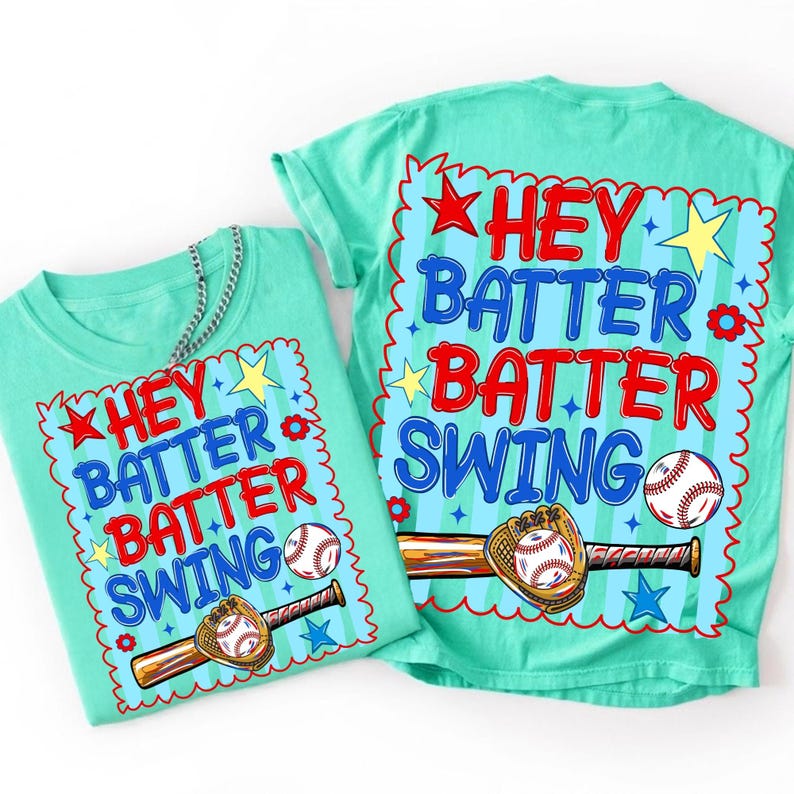 K&ouml;nnte beinhalten: Zwei t&uuml;rkisfarbene T-Shirts mit dem Text "HEY BATTER BATTER SWING" in Rot und Blau. Das Design umfasst einen Baseball, einen Schl&auml;ger und einen Handschuh. Die Shirts haben einen Rundhalsausschnitt und kurze &Auml;rmel. Eine silberne Kette ist auf einem Shirt drapiert.
