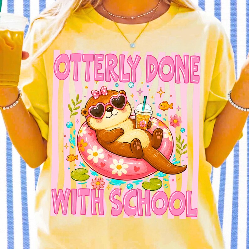 K&ouml;nnte beinhalten: Gelbes T-Shirt mit einer Grafik eines Otters mit herzf&ouml;rmiger Sonnenbrille und Schleife, der in einem rosa Schwimmring treibt. Der Text "OTTERLY DONE WITH SCHOOL" befindet sich &uuml;ber und unter der Otter-Illustration.