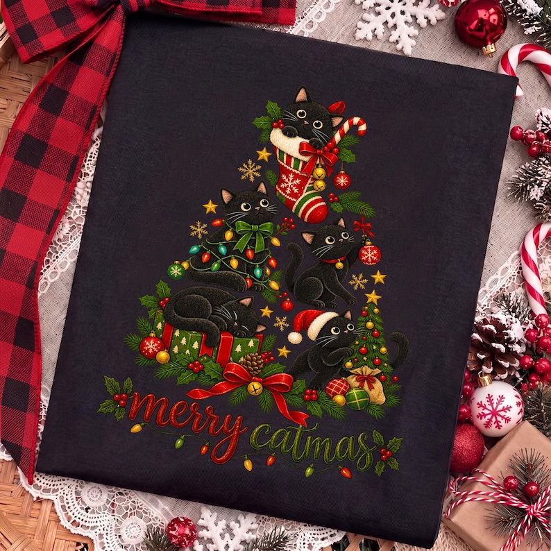 K&ouml;nnte beinhalten: Ein schwarzes T-Shirt mit einer Grafik von vier schwarzen Katzen in Form eines Weihnachtsbaums, verziert mit bunten Lichtern, Ornamenten und einem Weihnachtsstrumpf. Der Text "merry catmas" ist unten in Rot und Gr&uuml;n aufgedruckt.