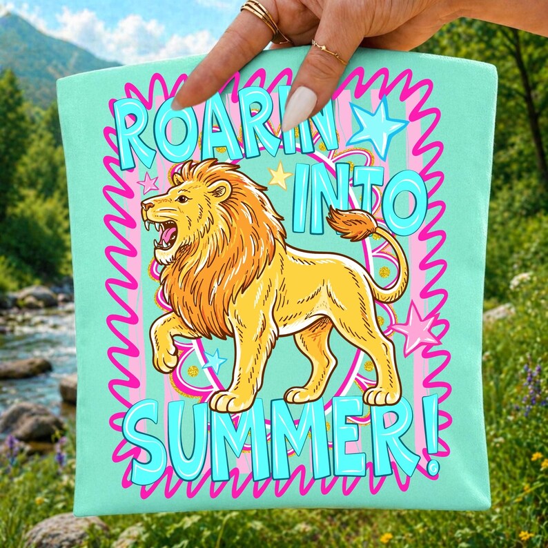 May include: A light teal tote bag with the words "ROARIN' INTO SUMMER!" in turquoise, outlined in pink. A cartoon lion with a yellow body and orange mane is featured. Stars and wavy lines complete the design.