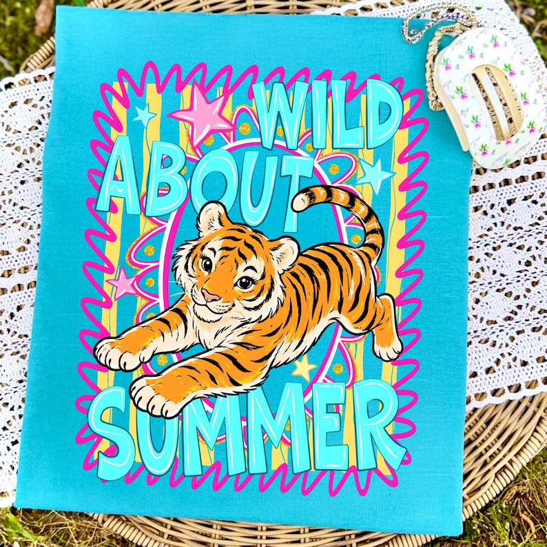 K&ouml;nnte beinhalten: Eine t&uuml;rkisfarbene Tragetasche mit einem farbenfrohen Design. Die Tasche zeigt einen Zeichentiger mit orangefarbenen und schwarzen Streifen und die Worte "WILD ABOUT SUMMER" in T&uuml;rkis, Rosa und Gelb. Das Design wird von einem rosa-gelben Rahmen umrandet.