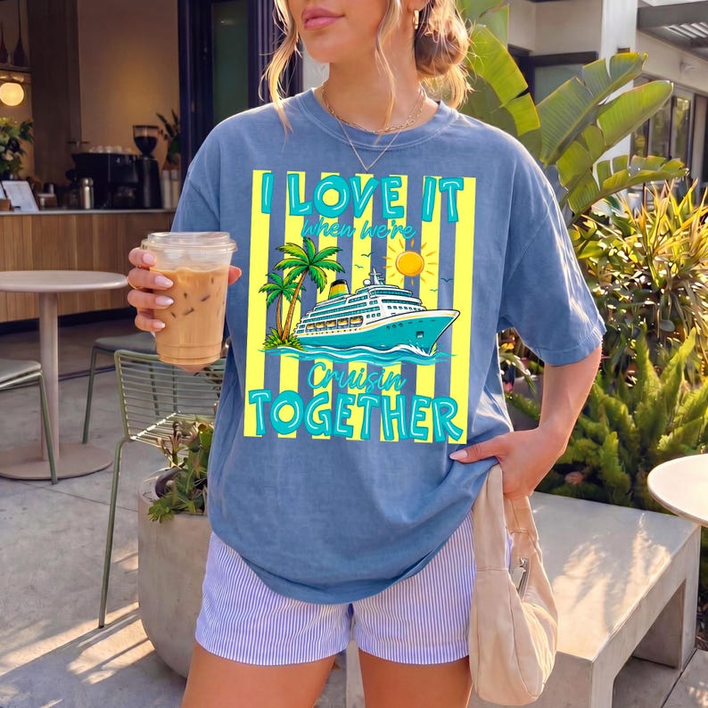 May include: Blue t-shirt with the text "I LOVE IT when we're Cruisin' TOGETHER" in turquoise and yellow. The graphic features a cruise ship, palm trees, and a sun. The shirt is paired with striped shorts.