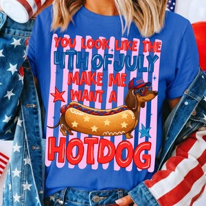 May include: Blue t-shirt with a graphic of a dachshund wearing sunglasses and a hat, inside a hotdog. The text reads "YOU LOOK LIKE THE 4TH OF JULY MAKE ME WANT A HOTDOG".