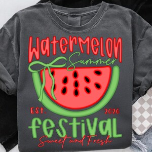 以下が含まれることがあります： スイカのスライスデザインと「Watermelon Summer Festival」の文字が赤と緑で描かれた濃いグレーのスウェットシャツ。「Est. 2026」と「Sweet and Fresh」の文字も含まれています。