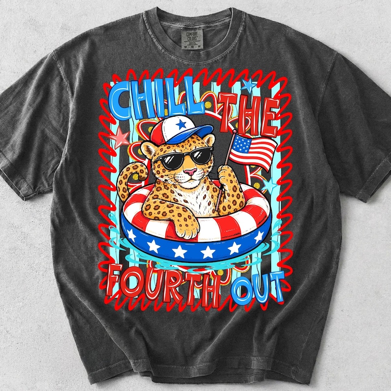 Op de afbeelding: Donkergrijze t-shirt met een luipaard met een zonnebril en een patriottische hoed, drijvend in een rood, wit en blauw zwemband. Het shirt heeft de tekst "CHILL THE FOURTH OUT" in een speels lettertype, ter viering van Independence Day.