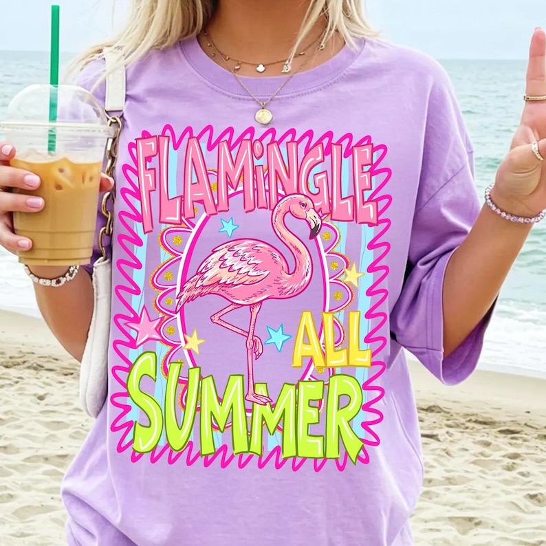 Puede incluir: Camiseta lila claro con un estampado de flamenco. El dise&ntilde;o incluye las palabras "Flamingle All Summer" en rosa y amarillo, con un flamenco rosa en el centro. La camiseta tiene mangas cortas.