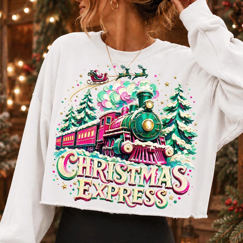May include: A white long-sleeve sweatshirt featuring a colourful graphic of a green and pink steam train travelling through a snowy forest. Above the train, a Santa sleigh flies with reindeer. The text CHRISTMAS EXPRESS is printed in large letters.