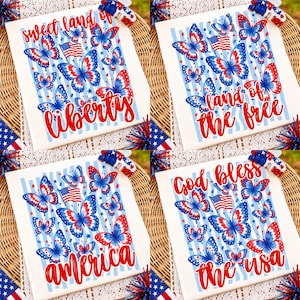 K&ouml;nnte beinhalten: Ein wei&szlig;es T-Shirt mit vier verschiedenen patriotischen Motiven mit rot-wei&szlig;-blauen Schmetterlingen, amerikanischen Flaggen und hellblauen vertikalen Streifen. Der Text lautet sweet land of liberty, land of the free, god bless und america the usa.