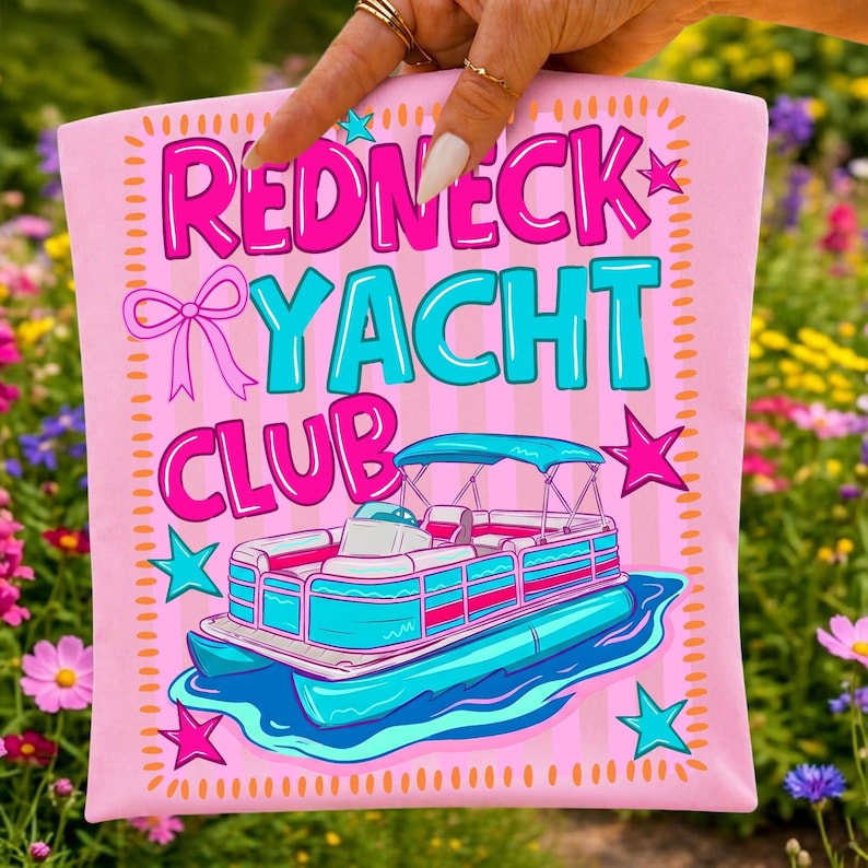 May include: Pink t-shirt with the words "Redneck Yacht Club" in pink and turquoise, along with a cartoon pontoon boat. The design includes stars and a bow, all set against a striped background.
