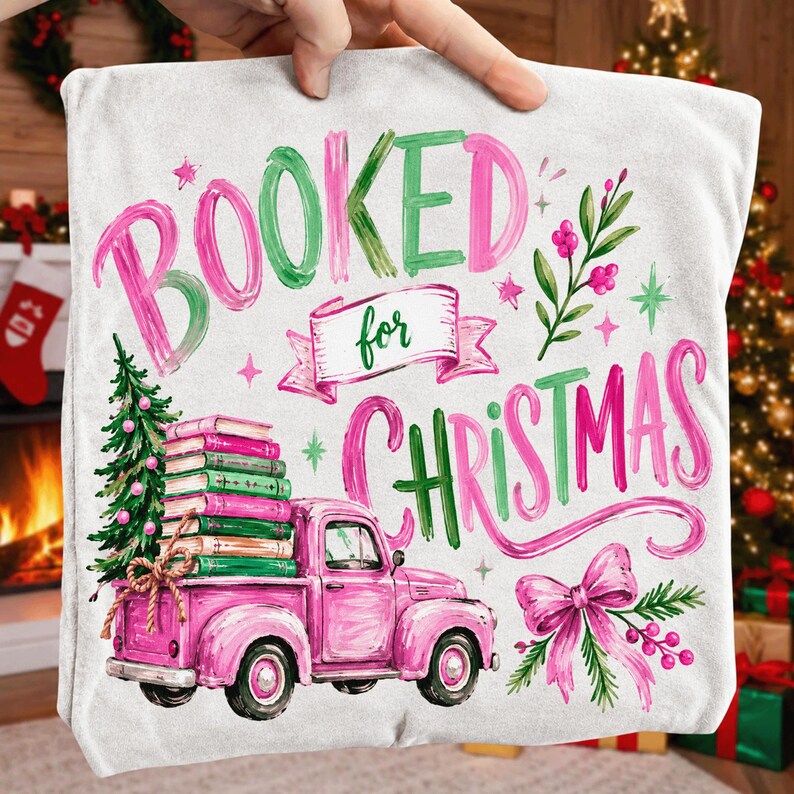 May include: A white throw pillow featuring a pink vintage truck carrying a stack of books and a small Christmas tree. The text reads "BOOKED for CHRISTMAS" in pink and green brush-style lettering, accented with a pink bow and festive greenery.