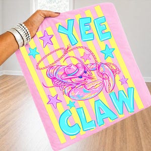 May include: Pink blanket with a cartoon lobster wearing a cowboy hat and the words "YEE CLAW" in turquoise. The blanket has yellow and pink stripes and turquoise and purple stars.