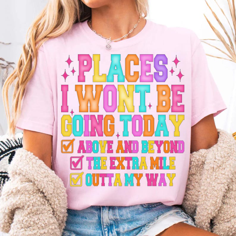 K&ouml;nnte beinhalten: Hellrosa T-Shirt mit dem bunten Schriftzug "PLACES I WON'T BE GOING TODAY". Darunter befinden sich drei Kontrollk&auml;stchen mit den Aufschriften "ABOVE AND BEYOND", "THE EXTRA MILE" und "OUTTA MY WAY".