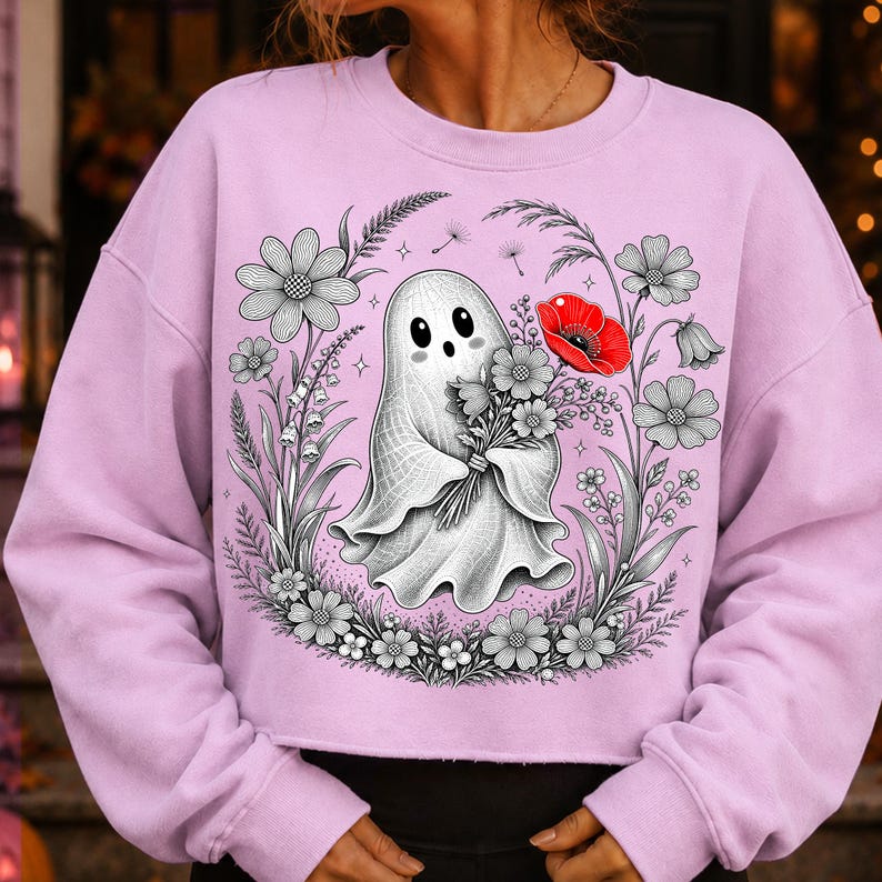 K&ouml;nnte beinhalten: Ein hellviolettes Langarm-Sweatshirt mit einer zentralen Grafik eines wei&szlig;en Geistes, der einen Blumenstrau&szlig; h&auml;lt. Der Geist ist von einer kreisf&ouml;rmigen Anordnung aus schwarz-wei&szlig;en Strichzeichnungen von Blumen umgeben, inklusive einer roten Mohnblume.