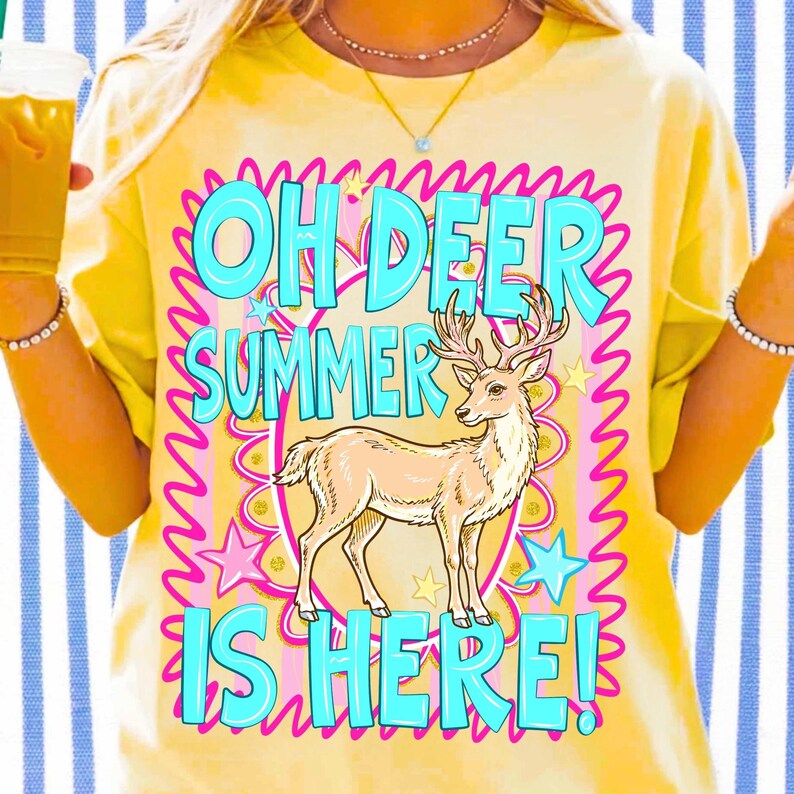 K&ouml;nnte beinhalten: Gelbes T-Shirt mit dem Text "OH DEER SUMMER IS HERE!" in T&uuml;rkis, umrandet von Pink. Eine Illustration eines beigen Hirsches befindet sich darunter, umgeben von rosa Sternen und Wellenlinien.