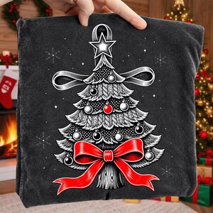 K&ouml;nnte beinhalten: Ein dunkelgraues T-Shirt mit einer grafischen Illustration eines stilisierten Weihnachtsbaums. Der Baum ist mit einer leuchtend roten Schleife an der Basis, einer roten Kugel, mehreren silbernen Kugeln und einem gro&szlig;en wei&szlig;en Stern geschm&uuml;ckt.