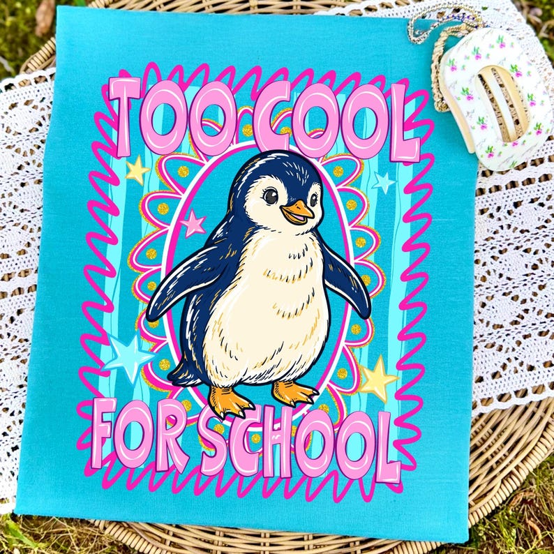 K&ouml;nnte beinhalten: Ein t&uuml;rkisfarbenes Handtuch mit dem Schriftzug "TOO COOL FOR SCHOOL" in rosa. Ein Cartoon-Pinguin ist das zentrale Bild, umgeben von Sternen und einem rosa und blauen Design. Der Pinguin hat einen wei&szlig;en Bauch, blaue Fl&uuml;gel und orangefarbene F&uuml;&szlig;e.