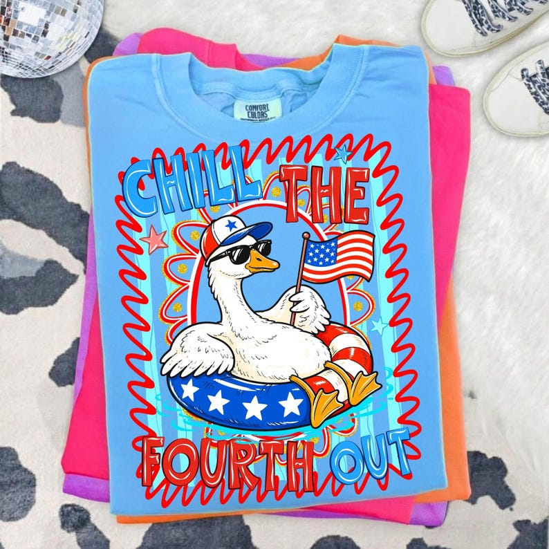 Peut inclure: T-shirt bleu clair Comfort Colors avec un motif d'oie portant des lunettes de soleil et un chapeau patriotique, tenant un drapeau am&eacute;ricain et flottant dans une bou&eacute;e ray&eacute;e rouge et blanche. Le texte "CHILL THE FOURTH OUT" est affich&eacute; en rouge et bleu.