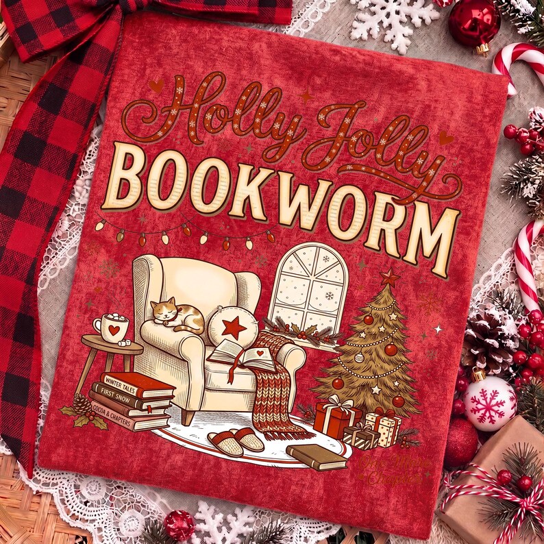 Op de afbeelding: Een rood stoffen vierkant met de tekst Holly Jolly BOOKWORM in bruin en cr&egrave;me. De illustratie toont een cr&egrave;mekleurige fauteuil met een slapende kat, een open boek, een stapel boeken, een kerstboom, cadeautjes en een raam met sneeuw.