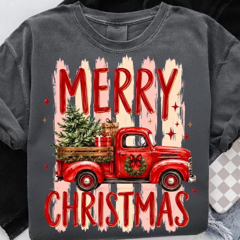 Może przedstawiać: Ciemnoszary t-shirt z grafiką czerwonego zabytkowego pickupa przewożącego choinkę i prezenty. Napis MERRY CHRISTMAS jest nadrukowany na czerwono nad i pod ciężar&oacute;wką, na tle pionowych pociągnięć pędzla.