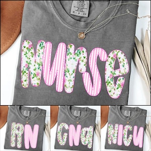 Puede incluir: Tres camisetas grises con letras rosas florales y a rayas. La primera camiseta dice "RN", la segunda dice "CNA" y la tercera dice "NICU".