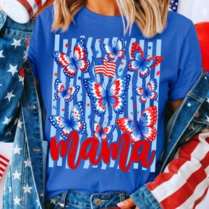 May include: A royal blue t-shirt featuring a graphic print of multiple butterflies with red, white, and blue patterns, a small American flag, and light blue vertical stripes. The word mama is printed in a large, bold, red cursive script font.