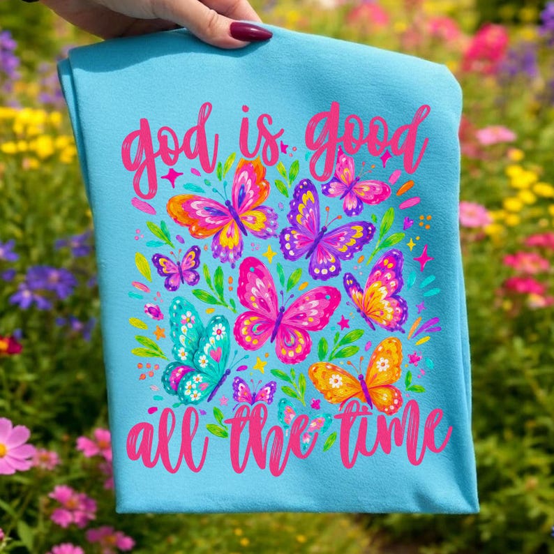 Peut inclure: Une serviette d&eacute;corative bleu clair avec le texte "god is good all the time" en script rose. La serviette pr&eacute;sente des papillons color&eacute;s dans les tons de rose, orange, violet et sarcelle, entour&eacute;s de feuilles vertes et d'&eacute;toiles.