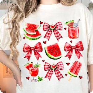 May include: White t-shirt featuring a red and white gingham bow, watermelon slices, and watermelon-themed drinks. The shirt has a red, white, and green colour scheme.