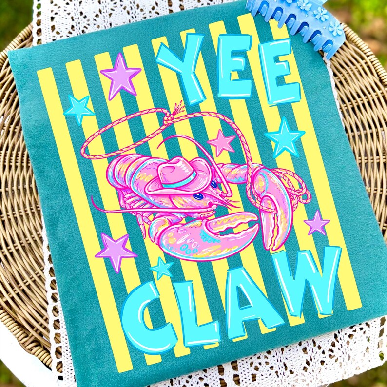May include: Teal pillow with yellow vertical stripes and the words "YEE CLAW" in turquoise block letters. A pink and blue lobster wearing a cowboy hat is in the center, surrounded by pink and turquoise stars.