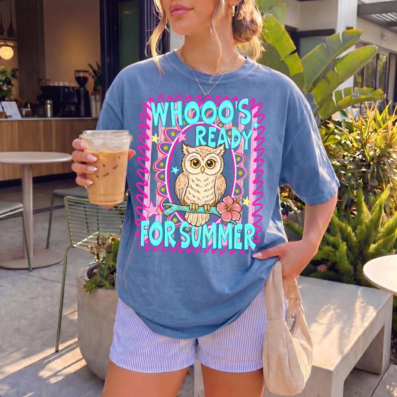 Peut inclure: T-shirt bleu avec l'inscription "WHOOO'S READY FOR SUMMER" et un dessin de hibou. Le hibou est perch&eacute; sur une branche avec une fleur. Le t-shirt est port&eacute; avec un short ray&eacute; et un sac &agrave; main beige.