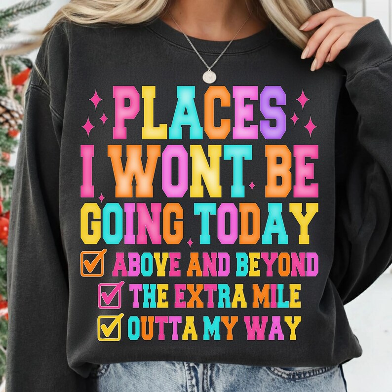 K&ouml;nnte beinhalten: Schwarzes Sweatshirt mit dem Text "PLACES I WONT BE GOING TODAY" in bunten Blockbuchstaben. Darunter befinden sich drei Kontrollk&auml;stchen mit den S&auml;tzen "ABOVE AND BEYOND", "THE EXTRA MILE" und "OUTTA MY WAY".