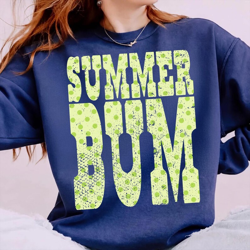 Puede incluir: Sudadera azul marino con la frase "SUMMER BUM" en letras grandes verde lima desgastadas. Las letras est&aacute;n salpicadas con peque&ntilde;os lunares verde claro. Un estilo casual y c&oacute;modo.