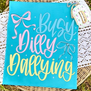 busy dilly dallying, coquette bow png, summer shirt design, sublimation graphic, dilly dallying png, hand lettered png, pastel typography, aesthetic png, dtf transfer design, digital download, summer season art, bow graphic png, girly apparel art