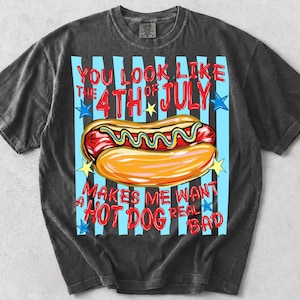 May include: Dark gray t-shirt with a graphic of a hot dog on a bun with mustard, and the text "YOU LOOK LIKE THE 4TH OF JULY MAKES ME WANT A HOT DOG REAL BAD" in red and blue.