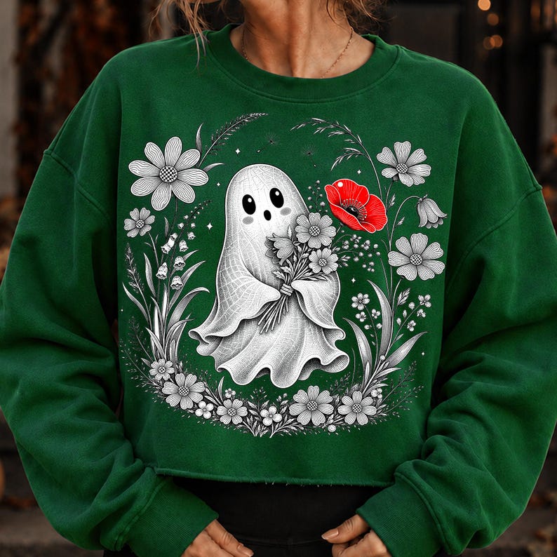 K&ouml;nnte beinhalten: Ein dunkelgr&uuml;ner Rundhals-Pullover mit einem zentralen Motiv eines wei&szlig;en Geistes, der einen Blumenstrau&szlig; h&auml;lt. Der Geist ist von einer kreisf&ouml;rmigen Anordnung aus schwarz-wei&szlig;en Strichzeichnungen von Blumen und einer roten Mohnblume umgeben.
