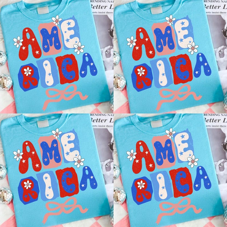 May include: Four light blue t-shirts, each featuring the word "AMERICA" in red, white, and blue, adorned with white flowers and a pink bow. The design is repeated on each shirt.