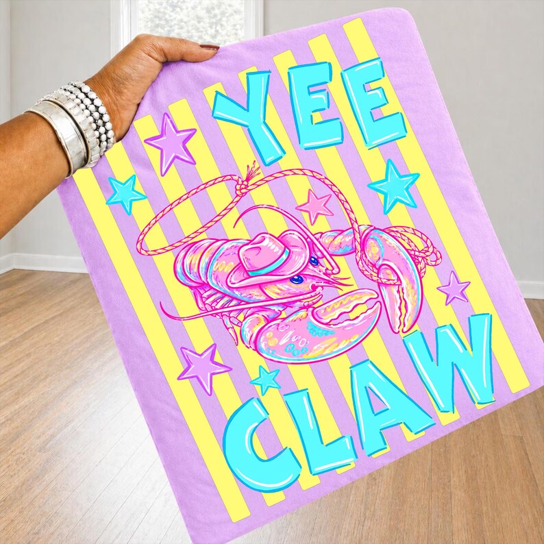 May include: A rectangular, lavender towel with yellow vertical stripes and the words "YEE CLAW" in turquoise. A pink lobster wearing a cowboy hat is in the center, surrounded by turquoise and pink stars.