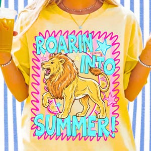May include: Yellow t-shirt with a graphic of a roaring lion and the text "ROARIN' INTO SUMMER!" in a pink and blue design. The lion is yellow and orange, with a pink and blue star and wave design around the text.