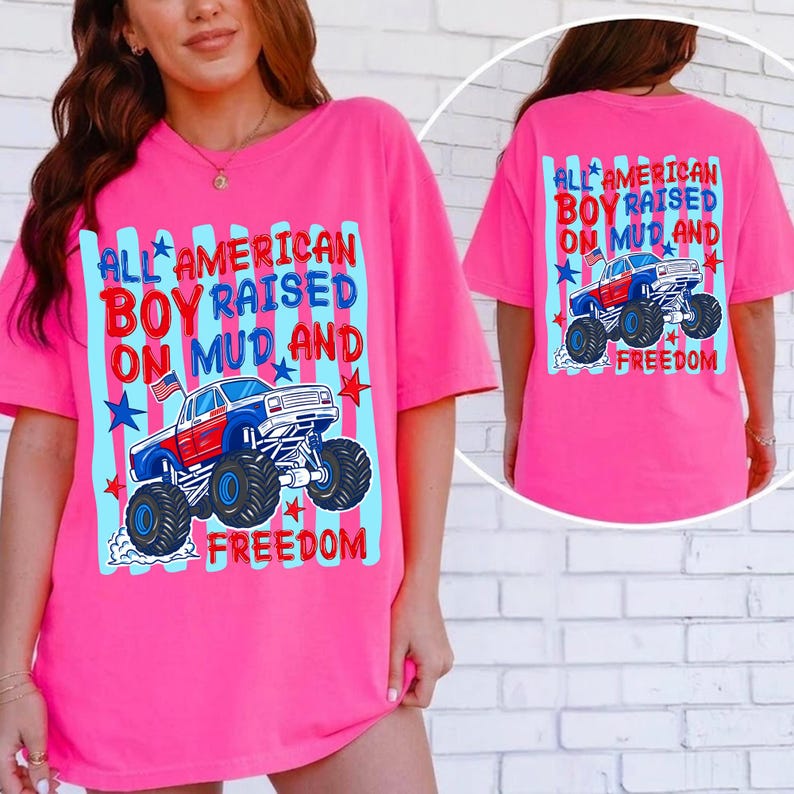 K&ouml;nnte beinhalten: Ein leuchtend pinkes T-Shirt mit dem Text "ALL AMERICAN BOY RAISED ON MUD AND FREEDOM" und einer Monster-Truck-Grafik. Das Design verwendet Rot, Wei&szlig; und Blau, mit Sternen und Streifen.
