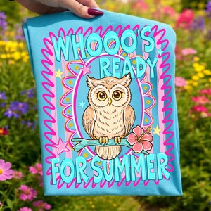 Peut inclure: Un t-shirt bleu clair avec un motif de hibou de dessin anim&eacute;. Le hibou est perch&eacute; sur une branche avec une fleur d'hibiscus rose. Le texte "WHOOO'S READY FOR SUMMER" est en turquoise, soulign&eacute; de rose, dans un cadre rose et turquoise.