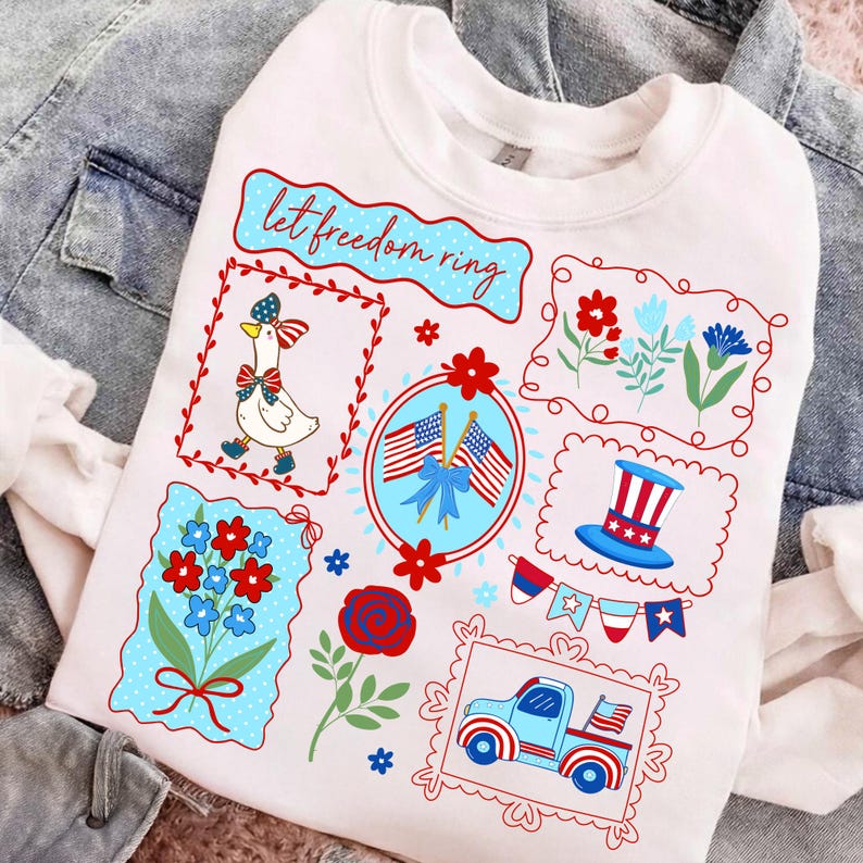 May include: White sweatshirt with patriotic graphics. Features a goose in a bow, American flags, flowers, a top hat, and a truck. The text "let freedom ring" is displayed in a blue banner. The design is in red, white, and blue.